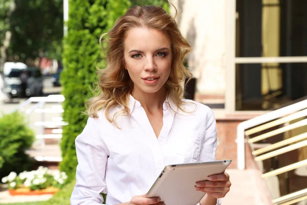 Beautiful young girl with tablet on city street — Stock Photo, Image