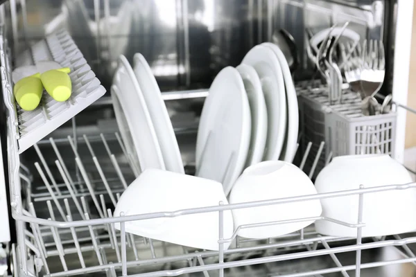 Відкрита посудомийна машина з чистим посудом в ній — стокове фото