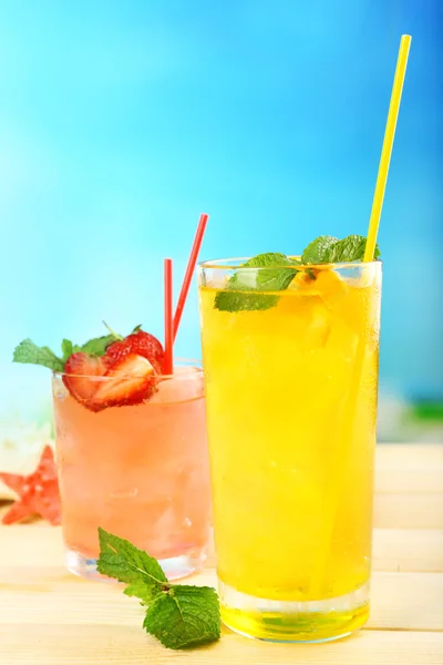 Refreshing cocktail on wooden table on blue background — Stock Photo, Image