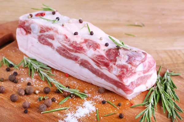 Raw bacon with spices on wooden table — Stock Photo, Image