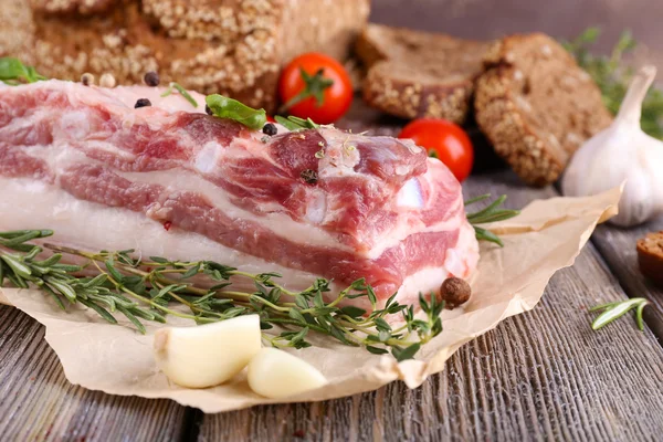 Rå bacon med bröd och kryddor på träbord — Stockfoto