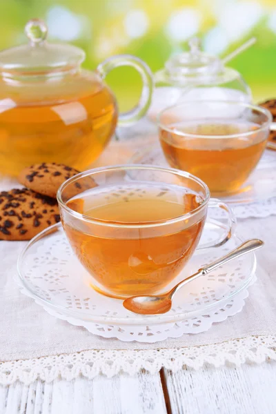 Bule e xícaras de chá na mesa em fundo brilhante — Fotografia de Stock