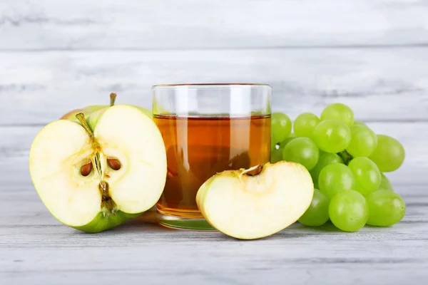 Bicchiere di succo con uva fresca e mele sul tavolo di legno grigio — Foto Stock