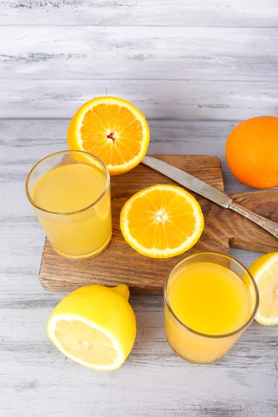 Copos de suco com frutas frescas na mesa de madeira cinza — Fotografia de Stock