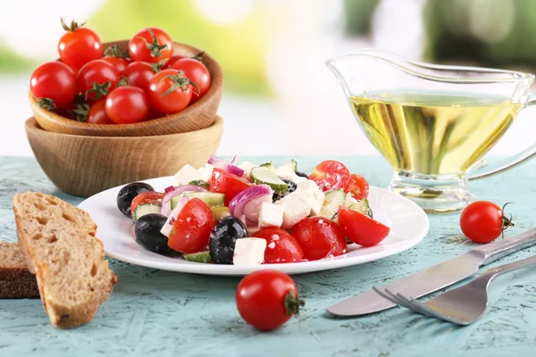 Salad Yunani di piring dan roti di atas meja kayu dengan latar belakang alami — Stok Foto