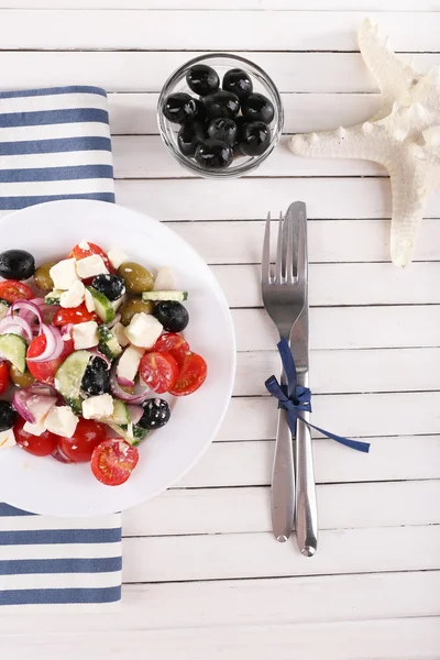 Salada grega servida em prato sobre guardanapo em fundo de madeira — Fotografia de Stock