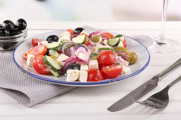 Salada grega servida em prato sobre guardanapo em mesa de madeira sobre fundo natural — Fotografia de Stock