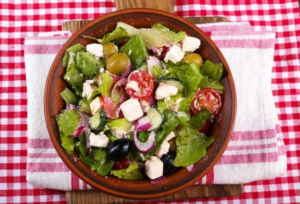 Schüssel griechischer Salat serviert auf Schneidebrett Serviette auf Holztisch auf dunklem Hintergrund — Stockfoto