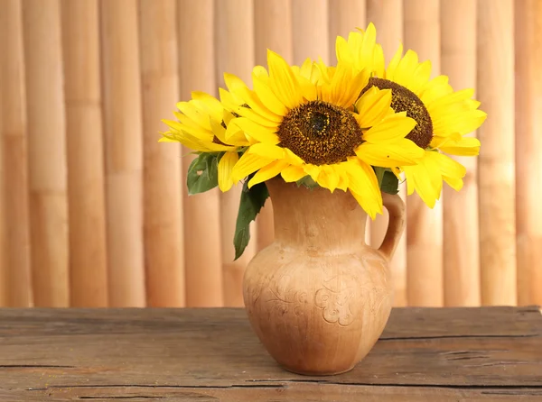 Schöner Strauß Sonnenblumen in Krug auf Tisch auf Holzgrund — Stockfoto