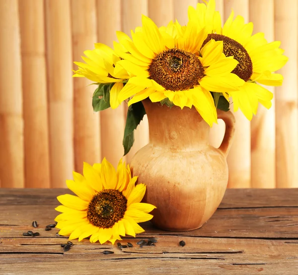 Beautiful bouquet of sunflowers in pitcher on table on wooden background — Stock Photo, Image