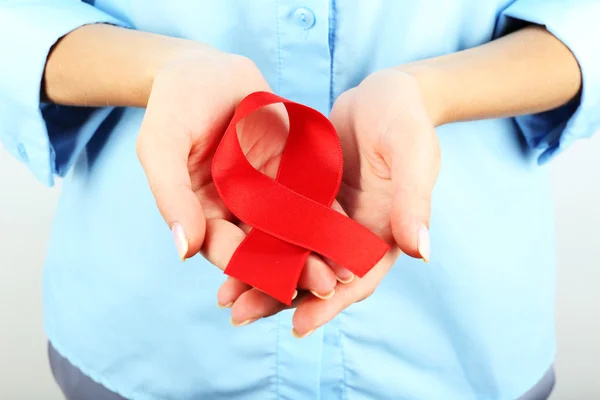 Woman holding red ribbon on light background — Stock Photo, Image