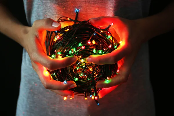 Woman holding multicoloured garland on dark background — Stock Photo, Image