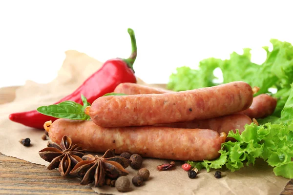 Smoked thin sausages  with lettuce salad leaves and spices on wooden cutting board, isolated on white — Stock Photo, Image