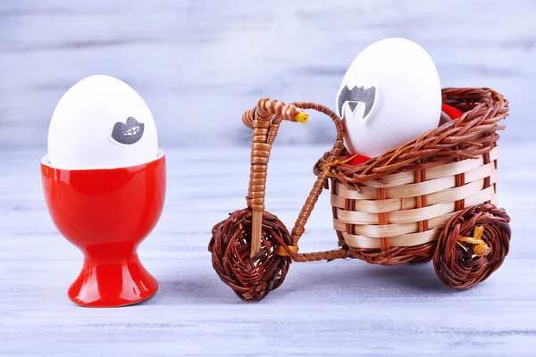 Яйца в яичных чашках и на велосипеде на сером деревянном фоне — стоковое фото