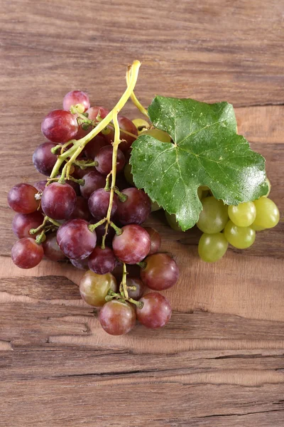 Ramos de diferentes tipos de uvas sobre fondo de madera — Foto de Stock