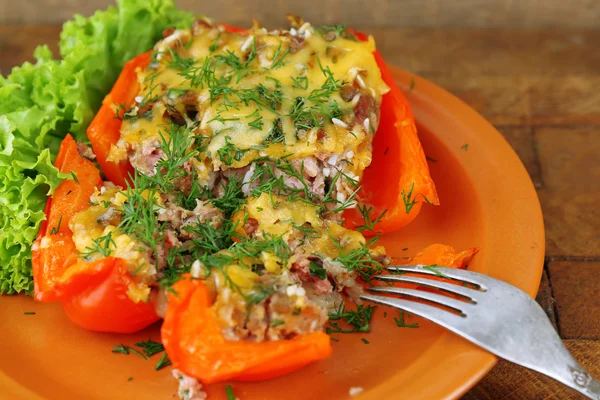 Stuffed red pepper with lettuce on plate on wooden table — Stock Photo, Image