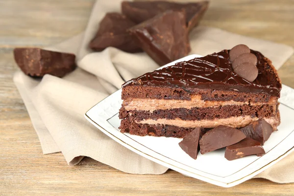 Chocolate cake on plate, on wooden background — Stock Photo, Image