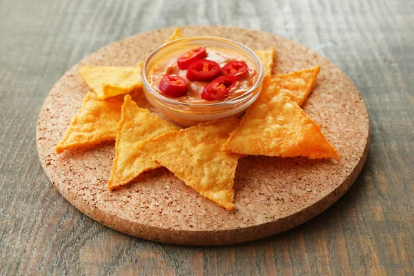 Välsmakande nachos och skål med sås ombord, på trä bakgrund — Stockfoto