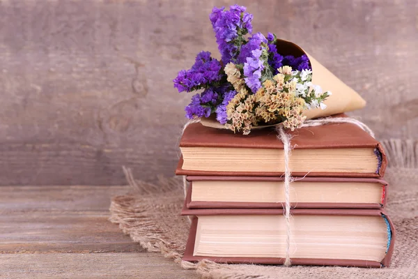 Boeken en wilde bloemen op servet op houten tafel op houten muur achtergrond — Stockfoto