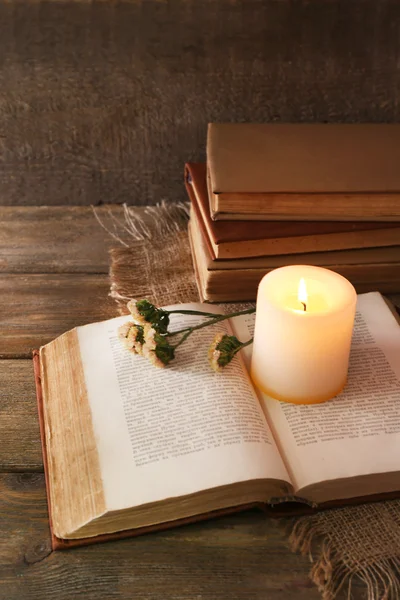 Книги, цветы и свечи на салфетке на деревянном столе на фоне деревянной стены — стоковое фото