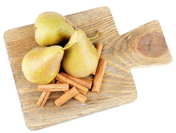 Peras maduras y varillas de canela sobre tabla de cortar de madera, aisladas en blanco — Foto de Stock