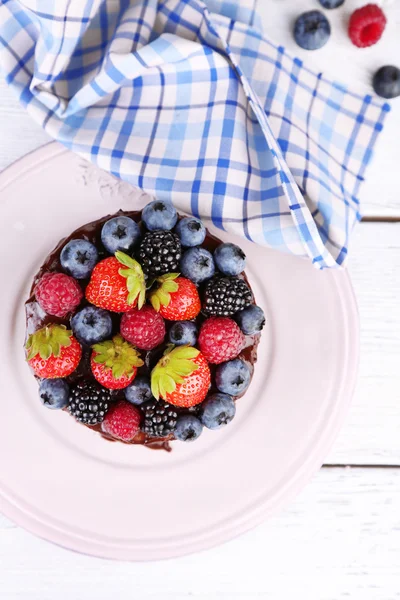 God chokladkaka med olika bär, på träbord — Stockfoto