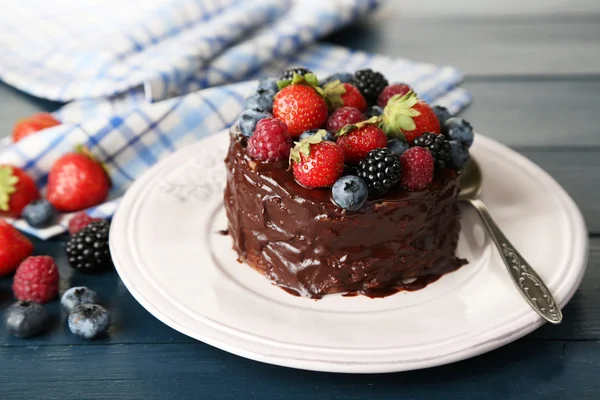 Leckerer Schokoladenkuchen mit verschiedenen Beeren, auf Holztisch — Stockfoto