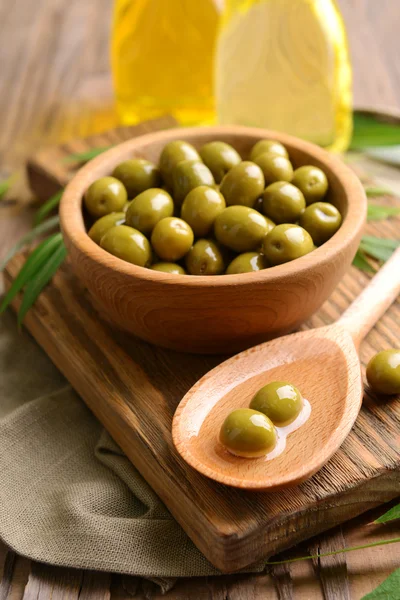 Green olives in bowl with leaves on table close-up — Stock Photo, Image