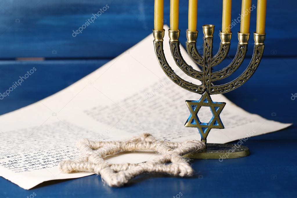 Menorah, star of David and page of Genesis book on wooden background