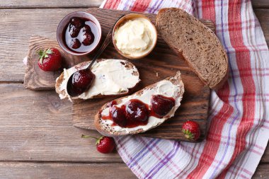 ahşap arka plan üzerinde ev yapımı tereyağı ve çilek reçel taze tost