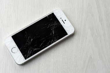 Ahşap arka planda kırık ekranlı modern cep telefonu