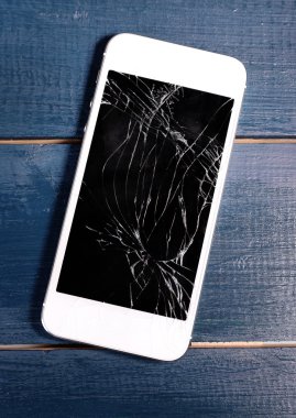 Ahşap arka planda kırık ekranlı modern cep telefonu