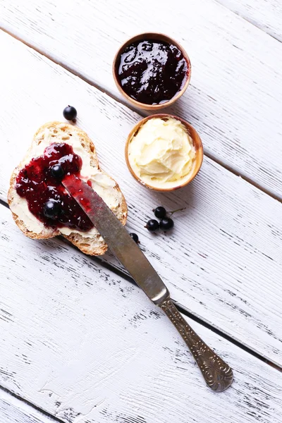 Pane fresco con burro fatto in casa e marmellata di ribes nero su fondo di legno chiaro — Foto Stock