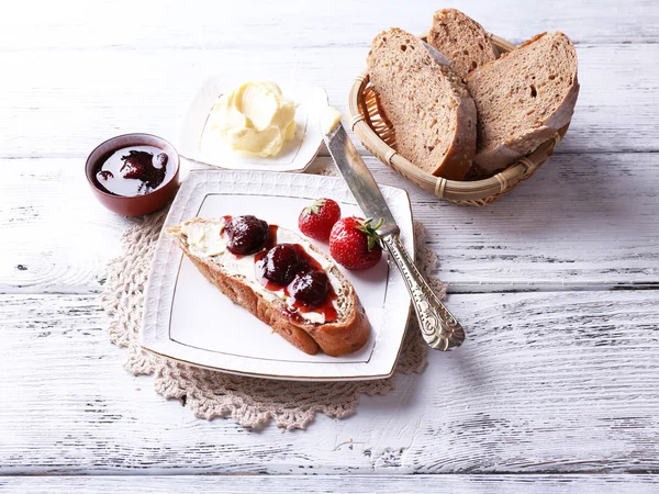 Čerstvé toasty s domácí máslem a jahodovým džemem, na světlé dřevěné pozadí — Stock fotografie