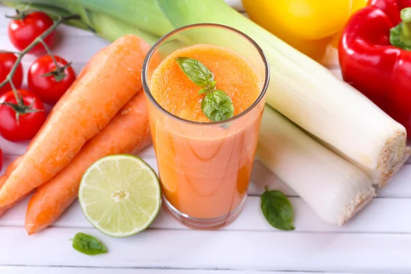 Glass of fresh carrot juice and vegetables on wooden background — Stock Photo, Image