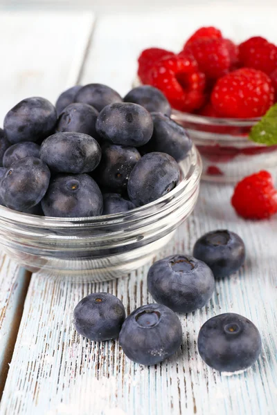 Glass bowls of raspberries and blueberries on wooden background — Stock Photo, Image