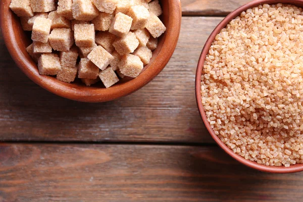 Cubes de sucre brun et sucre cristallin dans un bol sur fond en bois — Photo