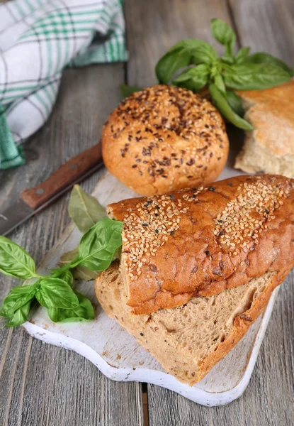 Świeżo pieczony chleb i świeżej bazylii na deski do krojenia, na tle drewniane — Zdjęcie stockowe