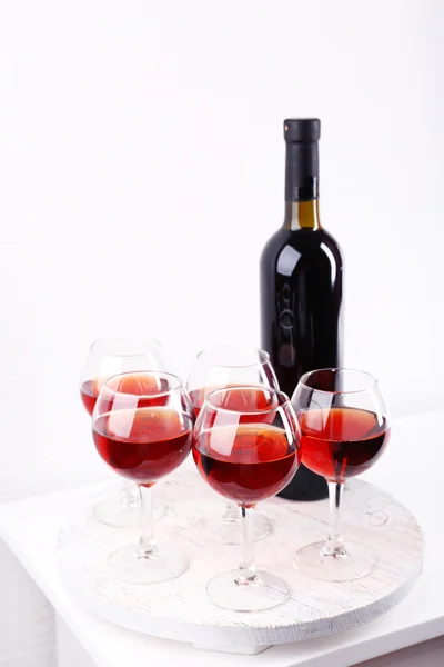 Glasses and wine bottle on tray in room — Stock Photo, Image