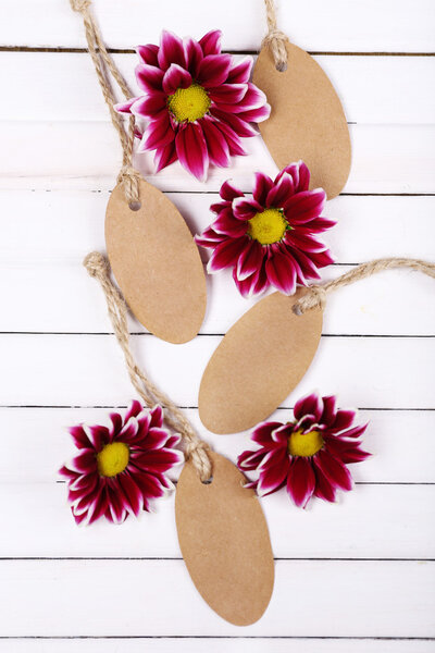 beautiful chrysanthemum flowers and empty tags on white wooden background