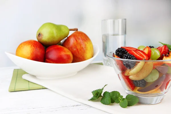 Välsmakande fruktsallad på bord, på ljus bakgrund — Stockfoto