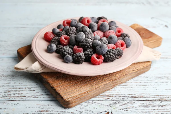 Iced berries on plate, on color wooden background — Stock Photo, Image
