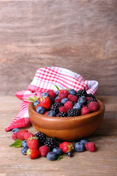 Ripe sweet different berries in bowl, on old wooden table — Stock Photo, Image