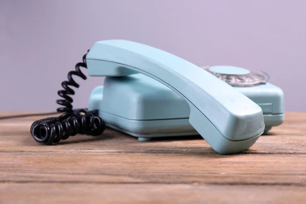 Retro turquoise telephone on wooden table, on color background — Stock Photo, Image