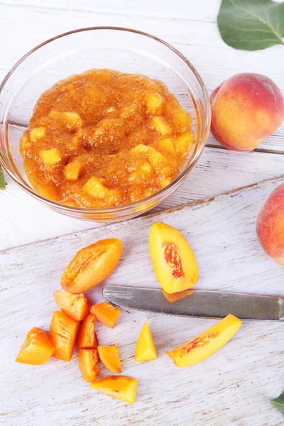 Leckere Pfirsichmarmelade mit frischen Pfirsichen auf Holztisch — Stockfoto