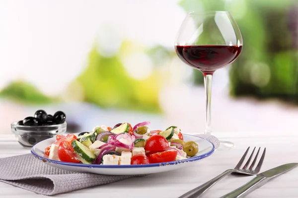 Salada grega servida em prato com copo de vinho — Fotografia de Stock
