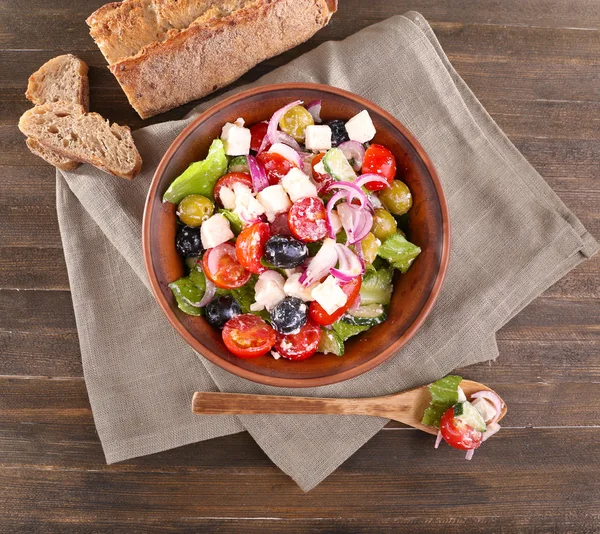 Greek salad served in brown bowl with bread — Stock Photo, Image