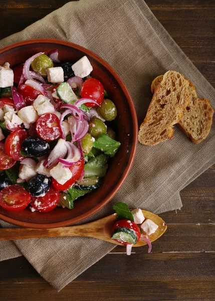 Greek salad served in brown bowl with bread — Stock Photo, Image