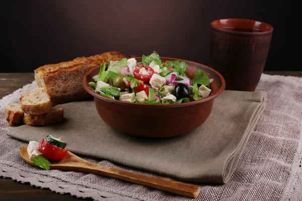 Greek salad served in bowl with slice of bread — Stock Photo, Image