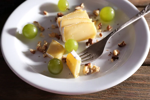 Smakelijke druif en kaas op plaat, op houten tafel — Stockfoto